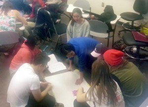 Photo of a group of college students seated on the floor and working on a map together